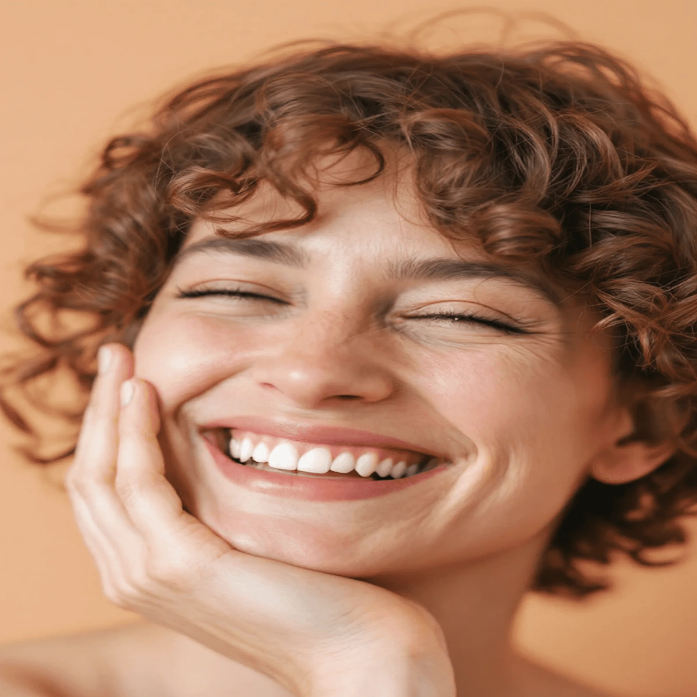 Smiling person with curly hair and closed eyes