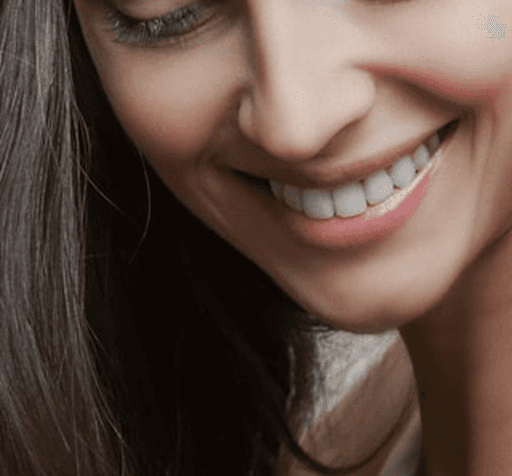 Smiling mouth with white teeth and dark hair.